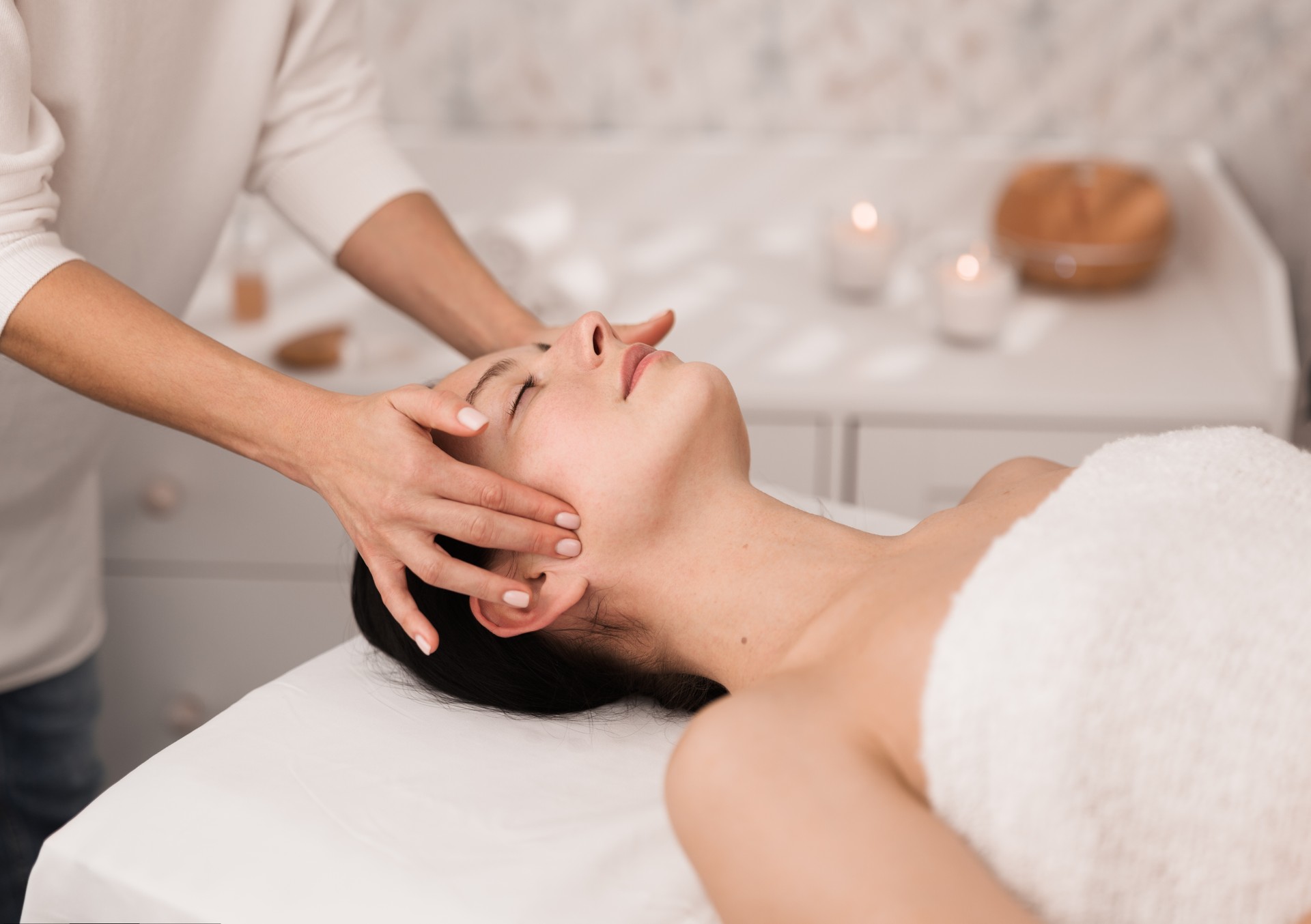 Crop unrecognizable therapist massaging face of female patient